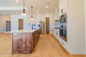 Kitchen featuring white cabinets, stainless steel refrigerator with ice dispenser, sink, backsplash, and a large island