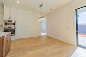 Kitchen with stainless steel double oven, white cabinets, and a healthy amount of sunlight