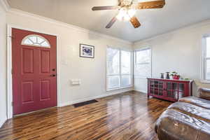 Entryway featuring ceiling fan, crown molding, and dark wood-type flooring