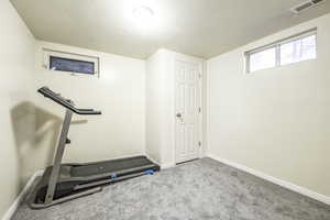 Workout area with light colored carpet and a textured ceiling