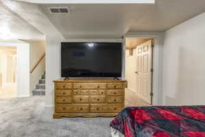 Bedroom featuring a textured ceiling and light carpet