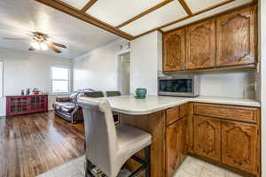 Kitchen with kitchen peninsula, light tile patterned floors, ceiling fan, and ornamental molding