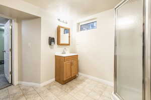 Bathroom with a textured ceiling, a shower with door, and vanity