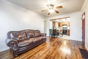 Living room featuring ceiling fan, crown molding, and light hardwood / wood-style floors