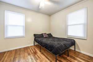 Bedroom with ceiling fan, crown molding, and hardwood / wood-style floors