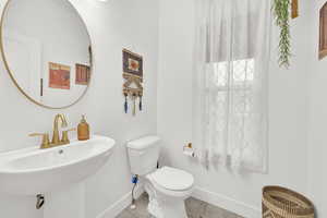 Bathroom with toilet, tile patterned flooring, and sink