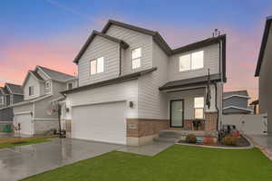 View of front facade featuring a garage and a yard