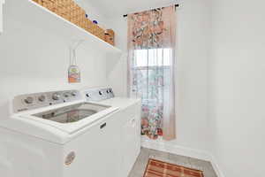 Clothes washing area featuring washing machine and dryer and light tile patterned flooring