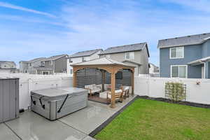 Back of property featuring a patio area, a gazebo, a hot tub, and an outdoor hangout area