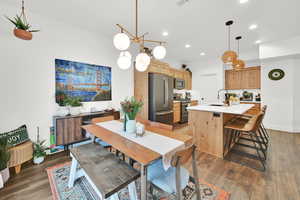 Dining space with dark hardwood / wood-style floors, sink, and a notable chandelier