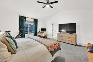 Carpeted bedroom featuring ceiling fan and vaulted ceiling