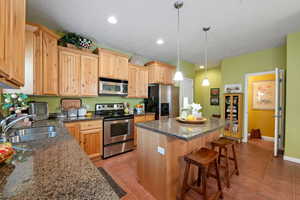 Kitchen featuring pendant lighting, a center island, stainless steel appliances, sink, and light tile patterned flooring