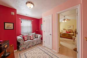 Sitting room with ceiling fan, light colored carpet, and a textured ceiling