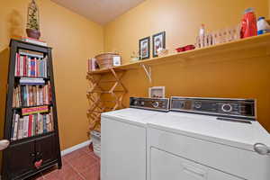 Laundry area featuring washer and dryer, a textured ceiling, and tile patterned floors