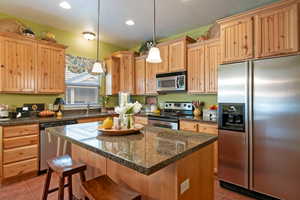 Kitchen featuring light tile patterned floors, hanging light fixtures, appliances with stainless steel finishes, and a center island