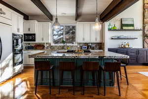 Kitchen with black appliances, dark stone countertops, white cabinetry, and a center island