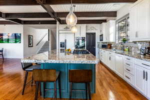 Kitchen featuring decorative light fixtures, white cabinetry, a center island, and black appliances