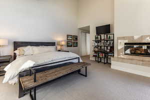 Carpeted bedroom featuring a towering ceiling and a tile fireplace