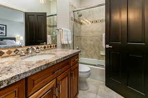 Full bathroom featuring combined bath / shower with glass door, toilet, tile patterned flooring, and vanity