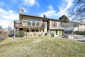 Back of house featuring central air condition unit, a deck, and a yard