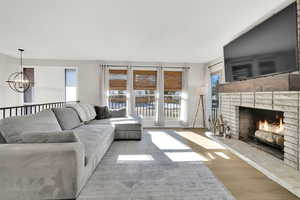 Living room featuring light wood-type flooring, a fireplace, and an inviting chandelier