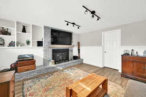 Living room with track lighting, a fireplace, and hardwood / wood-style flooring