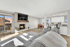 Living room featuring plenty of natural light, a stone fireplace, and light hardwood / wood-style floors