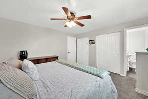 Bedroom with ceiling fan, carpet flooring, two closets, and connected bathroom