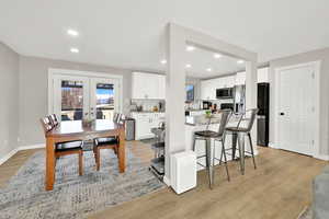 Kitchen featuring light wood-type flooring, white cabinets, french doors, and stainless steel appliances