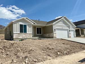 View of front of home with concrete driveway, board and batten siding, an attached garage, and stone siding