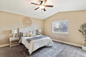 Bedroom featuring ceiling fan, dark carpet, and lofted ceiling