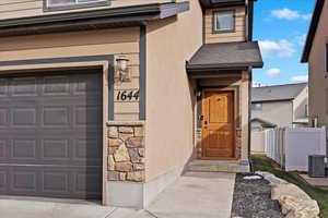 Doorway to property featuring a garage and central AC unit