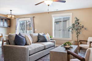 Living room featuring ceiling fan, dark wood-type flooring, and a wealth of natural light