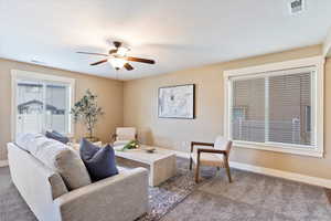 Living room featuring ceiling fan and dark carpet