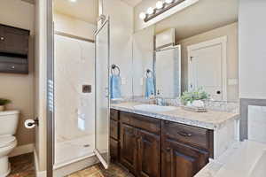 Bathroom featuring vanity, a shower with shower door, and toilet