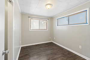 Empty room with ornamental molding and dark hardwood / wood-style flooring ADU