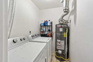 Laundry area with light tile patterned flooring, washer and dryer, a textured ceiling, and water heater