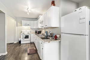 Kitchen with white appliances, a textured ceiling, white cabinetry, sink, and dark hardwood / wood-style floors ADU