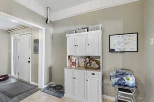 Interior space with electric panel, white cabinetry, ornamental molding, and light tile patterned  MAIN HOME