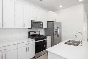 Kitchen featuring light stone countertops, white cabinets, gas range appliances with stainless steel finishes, sink, and light hardwood / wood-style flooring