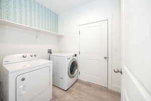 Laundry area featuring light wood-type flooring and washing machine and dryer