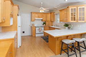 Kitchen with white appliances, tile counters, tasteful backsplash, sink, and kitchen peninsula