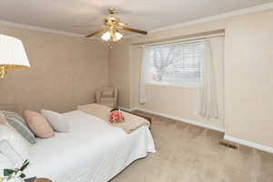 Carpeted bedroom featuring crown molding and ceiling fan