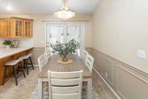 Carpeted dining area featuring an inviting chandelier