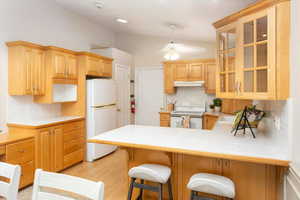 Kitchen featuring white appliances, a kitchen bar, decorative backsplash, kitchen peninsula, and tile countertops