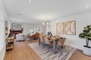 Dining area with an inviting chandelier, light hardwood / wood-style flooring, and a brick fireplace