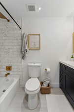 Full bathroom with vanity, toilet, tile patterned floors, and tiled shower / bath combo