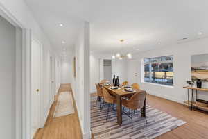 Dining space with a notable chandelier and light wood-type flooring