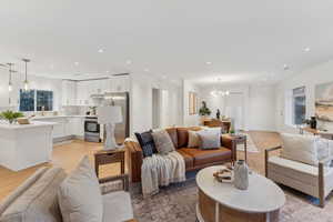 Living room with light hardwood / wood-style flooring and a notable chandelier