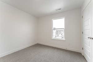 Spare room with carpet, visible vents, a textured ceiling, and baseboards